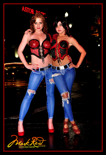 Black hared and red haired woman in front of the astor hotel in full body painting both in detailed jeans and corsets that are red and black